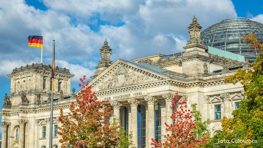 Reichstag building, seat of the German Parliament with national flag at sunset, Berlin